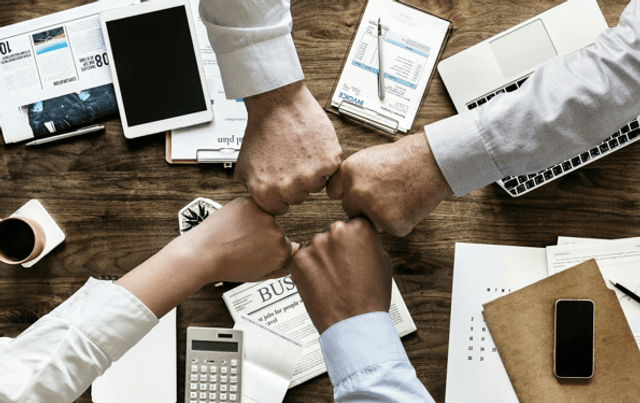 A four-way fist bump celebrating good corporate culture in the recruitment and mining industries in 