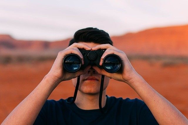 A man in the Australian mining industry looks through a pair of binoculars.