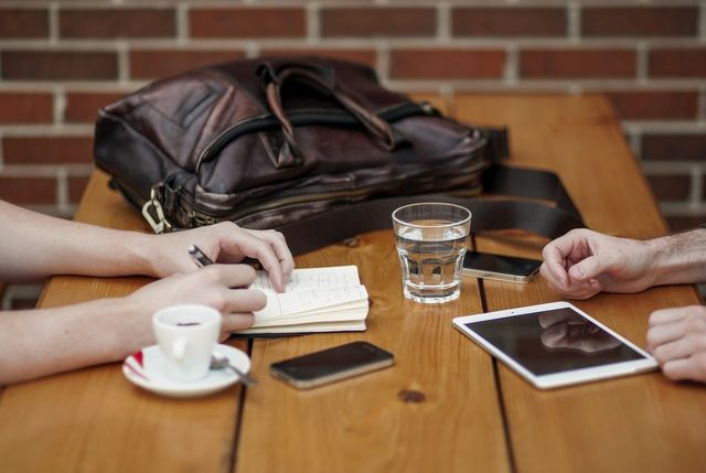 Water glass, espresso mug, smart devices on a cafe table