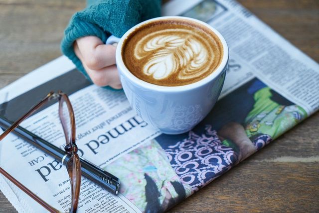 Latte, newspaper, glasses and pen