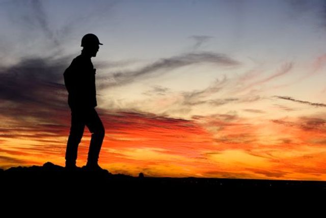 Silhouette of miner in front of a sunset