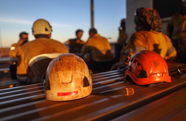 Group of miners chatting with hardhats on the table behind them