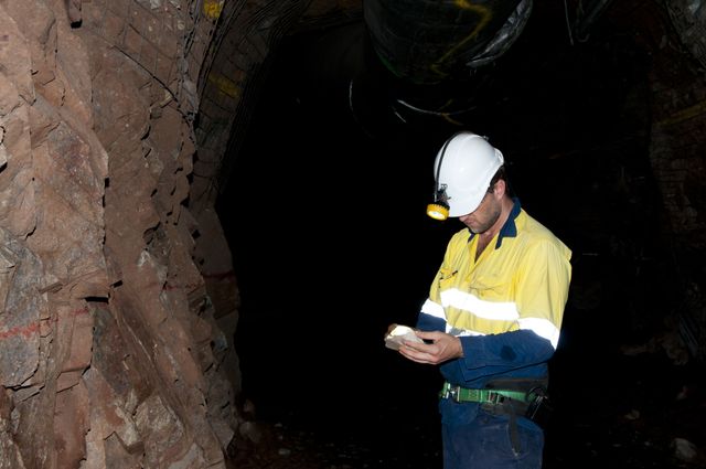 Mining engineer underground inspecting piece of rock