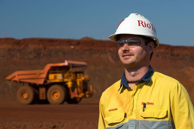 Miner wearing a Rio Tinto hard hat and a truck in the background