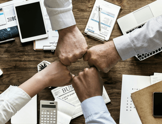 A four-way fist bump celebrating good corporate culture in the recruitment and mining industries in 