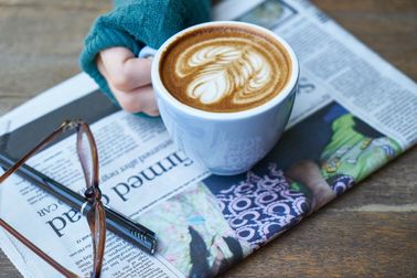Latte, newspaper, glasses and pen