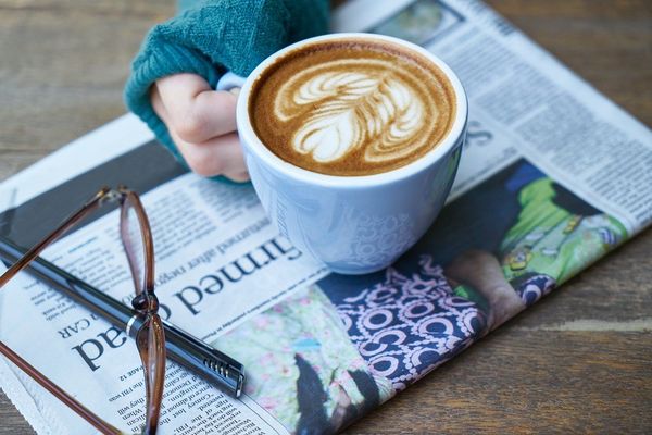 Latte, newspaper, glasses and pen