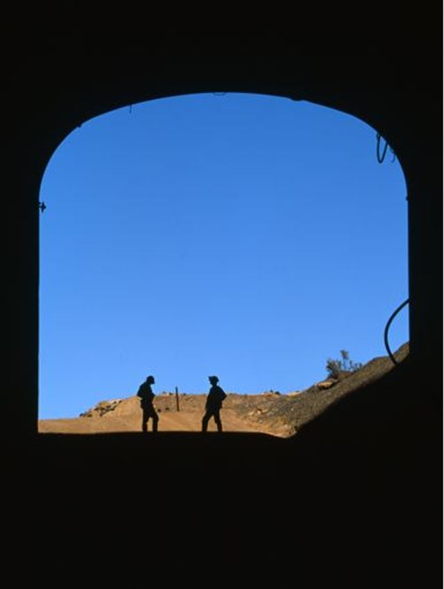 Silhouette of 2 miners outside a mine shaft