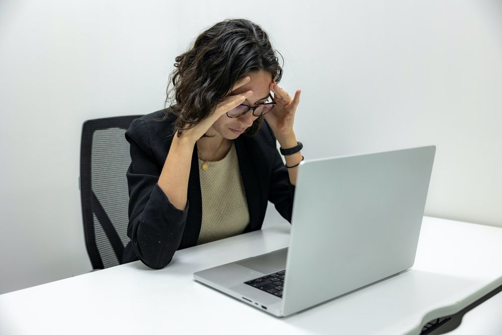lady looking into a laptop with her hand on her temples
