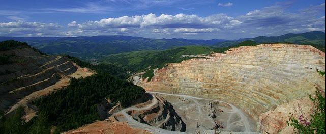 Open cut mine with green mountains in the background
